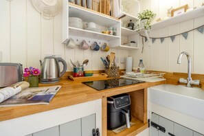 Eine kleine Küche mit Backofen, Kaffeemaschine und Spüle.