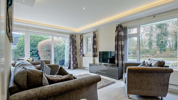 A modern living room with a sofa, armchair, and a flat-screen TV. - 2 Bed in Christchurch (oc-93458) (Christchurch)
