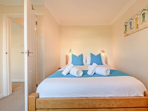 Ein Schlafzimmer mit einem hölzernen Bett, weißer Bettwäsche und blauen Kissen.