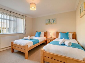 A hotel room with two wooden beds, a window with blinds, a lamp, and a painting on the wall. - 3 Bed in Christchurch (oc-93459) (Christchurch)