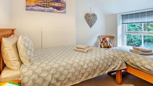 A bedroom with a bed, pillows, a heart-shaped decoration, a teddy bear, and a window with a view of greenery. - 2 Bed in Penrith (oc-93492) (Glenridding)