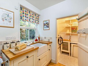 A kitchen with a wooden countertop, a sink, and a window with a view of greenery. There are cabinets, a refrigerator, and a washing machine visible. - 2 Bed in Penrith (oc-93492) (Glenridding)