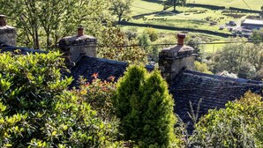 A rural landscape with stone chimneys, lush greenery, and a distant view of a valley. - 2 Bed in Penrith (oc-93492) (Glenridding)