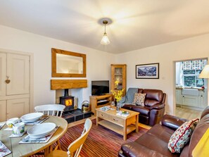 A cozy living room with a fireplace, a television, a dining table with chairs, and a leather sofa. - 2 Bed in Penrith (oc-93492) (Glenridding)