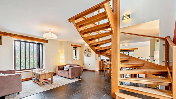 Un vaste espace de vie comprenant un escalier en bois, un canapé, une table basse et un coin repas.