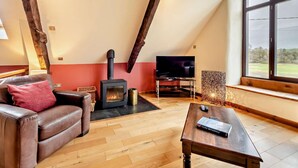 Une pièce de style loft avec une cheminée, un téléviseur, un canapé en cuir et une grande fenêtre.