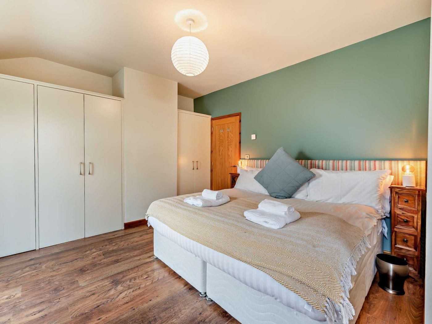 Une chambre à coucher comprenant un lit, une armoire, une table de chevet et un luminaire suspendu.
