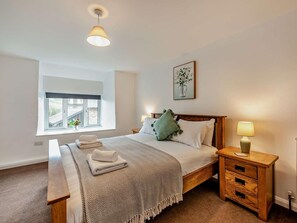A bedroom with a bed, bedside tables, a bench, a window, and a wall-mounted lamp. - 7 Bed in Bideford (oc-93523) (Weare Giffard)