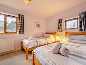 A bedroom with two beds, a radiator, a window with curtains, and a picture on the wall. - 3 Bed in Keswick (oc-93590) (Threlkeld)