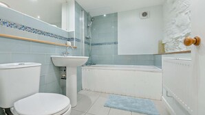 Kylpyhuone, jossa on wc, pesuallas, suihku ja kylpyamme.