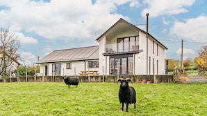 A two-story house with a balcony, a fenced yard, and two black sheep. - 3 Bed in Keswick (oc-93589) (Threlkeld)