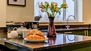 A kitchen counter with a plate of croissants, a teapot, and a vase with flowers. - 3 Bed in Keswick (oc-93589) (Threlkeld)
