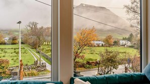 A room with a large window offering a view of a rural landscape, a stone wall, and a pathway. - 3 Bed in Keswick (oc-93589) (Threlkeld)