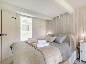 Ein Schlafzimmer mit einem Bett, einem Nachttisch und einer Tür.