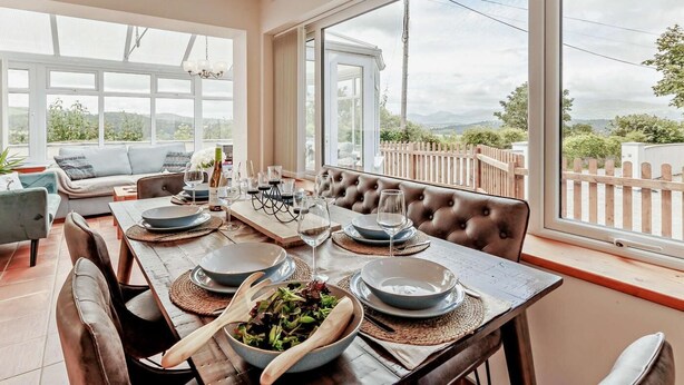 A dining area with a table set for a meal, a sofa, and a view of the outdoors. - 2 Bed in Llandudno Junction (oc-93622) (Bryn Pydew)