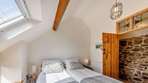 A bedroom with a sloped ceiling, a stone wall, a wooden door, and a skylight. - 2 Bed in Llandudno Junction (oc-93622) (Bryn Pydew)