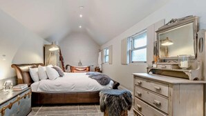 Ein Schlafzimmer mit einem großen Bett, einem Schminktisch, einem Frisierkommode und einem kleinen Tisch sowie einem Fenster.