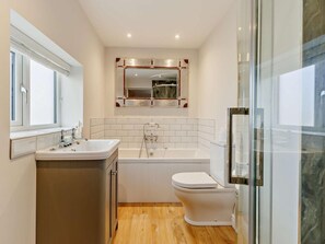 Ein modernes Badezimmer mit Waschbecken, Toilette, Badewanne und einer Duschkabine aus Glas.