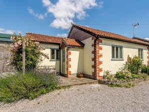 Ein eingeschossiges Haus mit Satteldach, einem Backsteinsschornstein und einer kleinen Veranda.