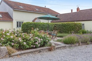 Ein Haus mit Terrasse, Tisch und Stühlen sowie einem grünen Sonnenschirm.
