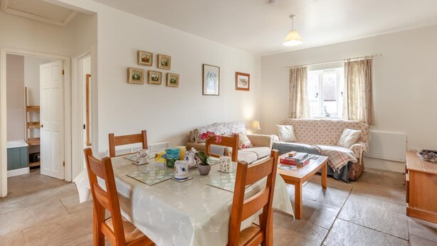 Una sala acogedora con un sofá, una mesa de comedor con sillas y una zona de cocina con armarios.