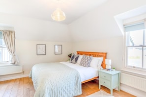 Une chambre à coucher avec un lit, une table de chevet, une lampe et une fenêtre.
