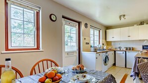 A kitchen with a dining area, a clock, and a washing machine. - 2 Bed in Bembridge (oc-ic042) (Bembridge)