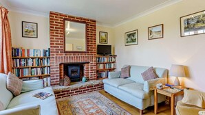 A living room with a fireplace, bookshelves, a sofa, a coffee table, and a rug. - 2 Bed in Bembridge (oc-ic042) (Bembridge)