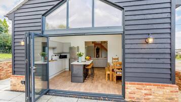 A modern kitchen with a large window, a dining area with wooden furniture, and a brick exterior.