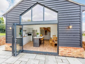 A modern kitchen with a large window, a dining area with wooden furniture, and a brick exterior.