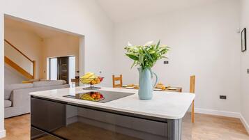 A modern kitchen with a central island, a dining area with a table and chairs, and a staircase leading to another level.