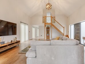 A spacious living room with a large sectional sofa, a flat-screen TV, and a wooden entertainment unit.