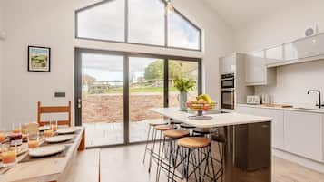 A modern kitchen with a large island, bar stools, and a dining area with a table set for breakfast.