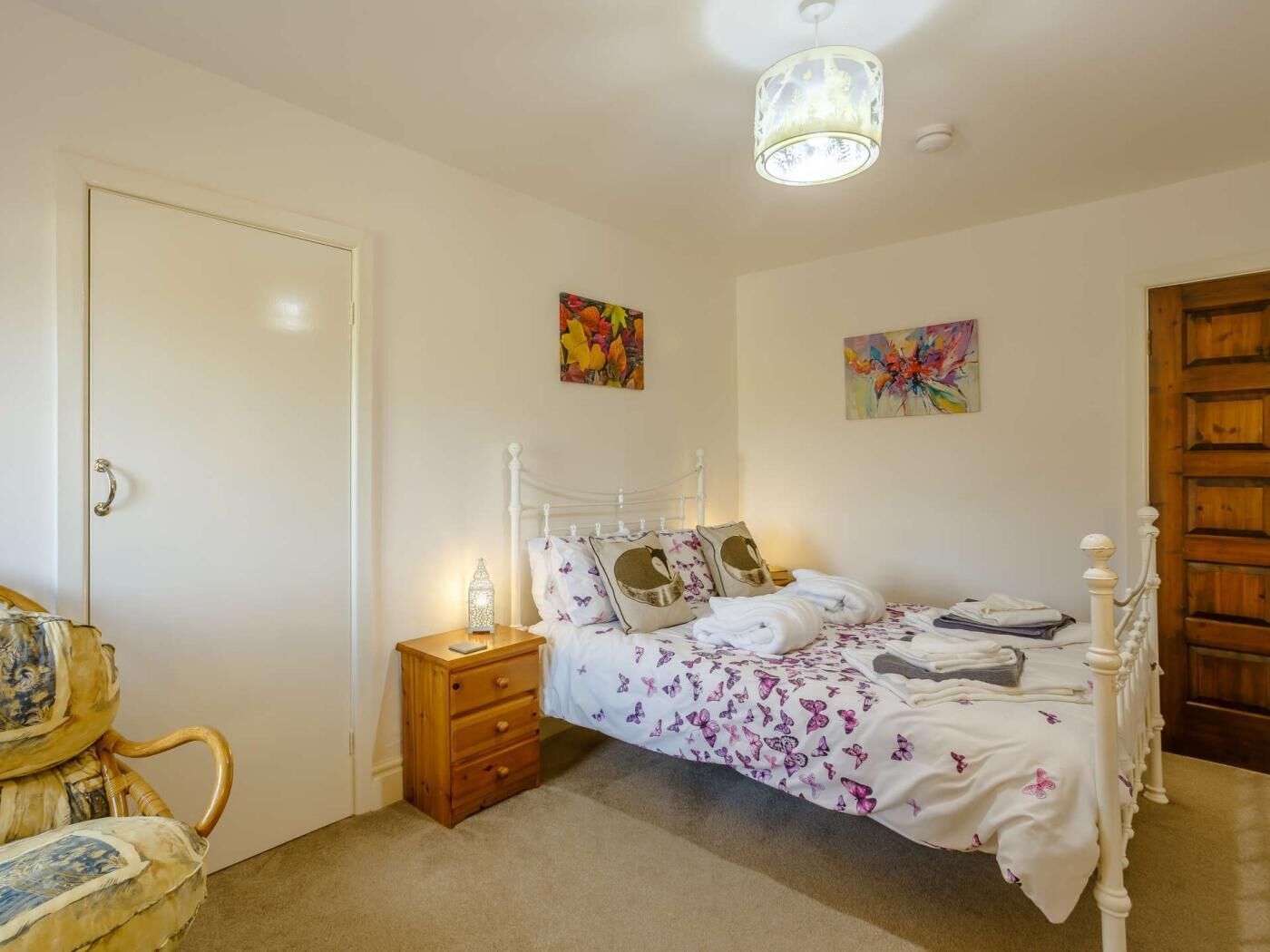 Une chambre à coucher avec un lit, une table de chevet, une lampe et deux tableaux au mur.