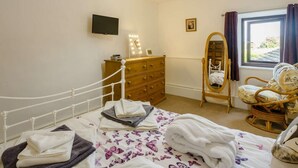 Un dormitorio con cama, cómoda, espejo y ventana con cortinas.