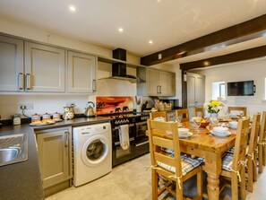 Una cocina moderna con electrodomésticos de acero inoxidable, sillas de madera y una mesa de comedor preparada para seis personas.