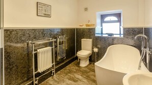 Un baño con una bañera independiente, un inodoro y un radiador.