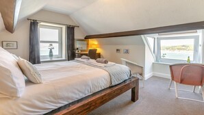 A bedroom with a large bed, a window with curtains, a chair, and a desk with a lamp. - 2 Bed in Appledore (oc-gable) (Appledore)