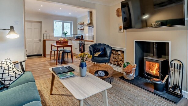 Een moderne woonkamer met een open haard, een eethoek en een keuken op de achtergrond.
