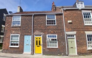 A two-story brick building with multiple windows and doors, including a yellow door and a green door.