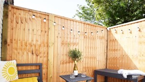 Een houten terras met een bed, een tafel en een bank.