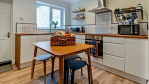 Een moderne keuken met een houten tafel, twee stoelen, een magnetron en een roestvrijstalen afzuigkap.