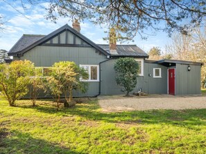A two-story house with a grey exterior, a red door, and a small attached shed. - 2 Bed in Brockenhurst (oc-94003) (Beaulieu)