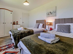 Ett hotellrum med två sängar, en garderob, ett nattduksbord med en lampa och en tavla på väggen.