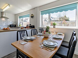 A modern kitchen with a dining area, white cabinetry, and a view of the neighborhood. - 3 Bed in Bude (oc-09117) (Crackington)
