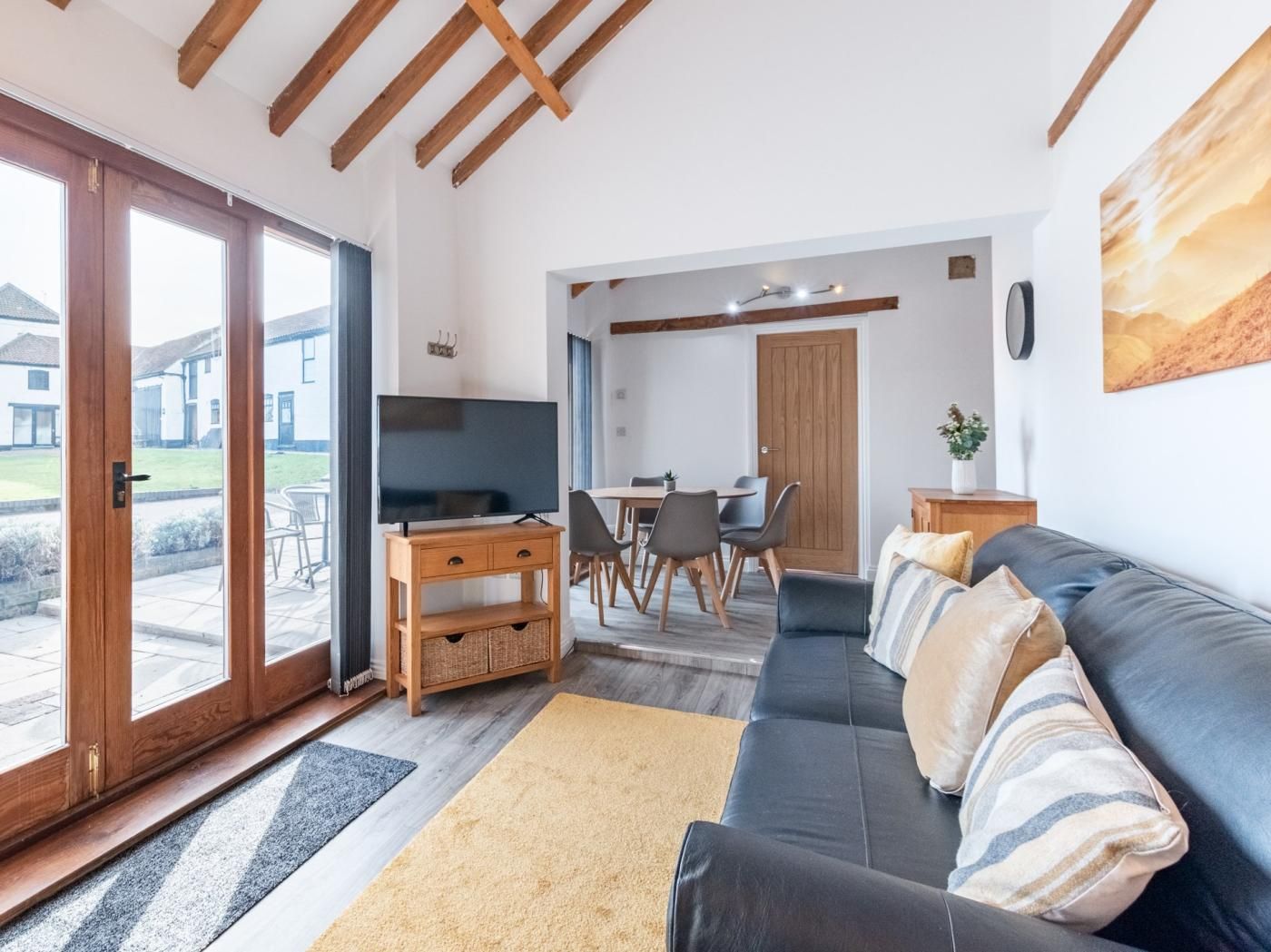 Een woonkamer met een bank, televisie en een eethoek.