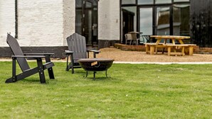 Une terrasse avec deux fauteuils Adirondack, un foyer et une table en bois.