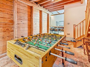 Ein Zimmer mit Holzboden, einer Tischfußballplatte, einer Treppe und Blick auf ein Gebäude.