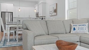 Ein modernes Wohnzimmer mit einem grauen Sofa, einer hölzernen Schale auf einem Tisch und einer weißen Wand mit einem gerahmten Bild.