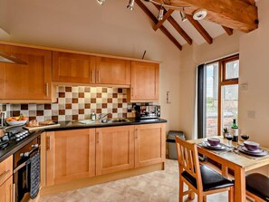 Eine Küche mit Holzausstattung, einer karierten Spritzschutzwand, einem Esstisch mit Stühlen und einem Fenster mit Blick.